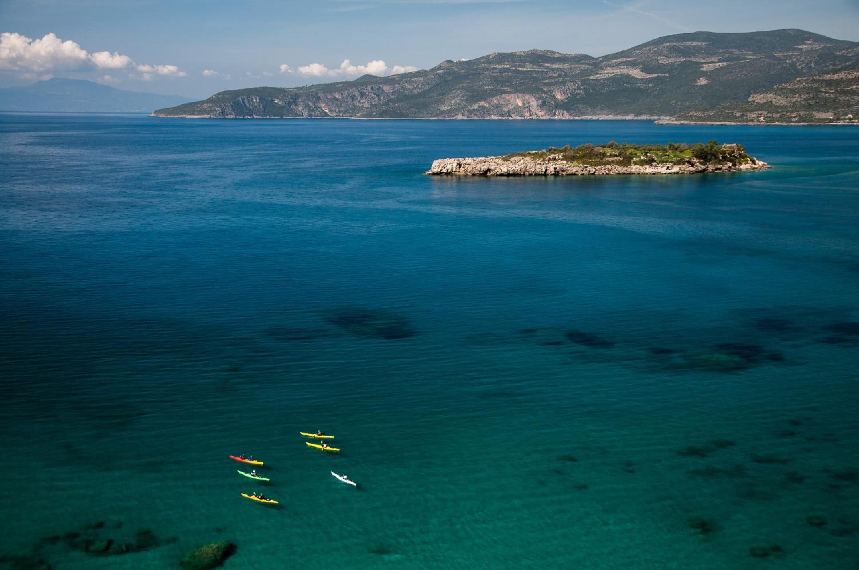 A coastal scene with kayaks on the water and a small island with rocky terrain.