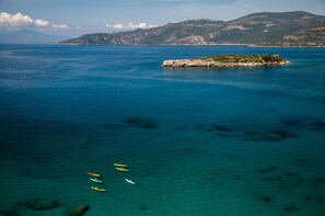 Escena costera con kayaks en el agua y una pequeña isla de terreno rocoso.