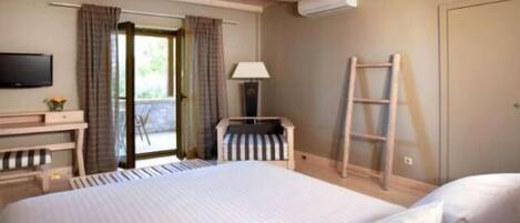A hotel room with a bed, a desk, a chair, a TV, a lamp, and a ladder.