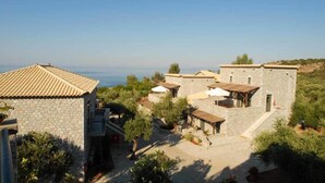 Ein Gebäude aus Stein mit einem Ziegeldach, umgeben von viel Grün und freiem Blick auf das Meer.
