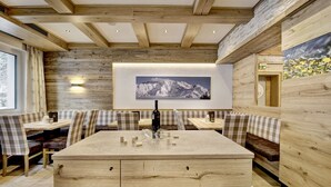 A modern dining area with wooden walls, a central island with a sink, and checkered booth seating. - Hotel-Restaurant Bike&Snow Lederer (Muehlbach Am Hochkoenig)
