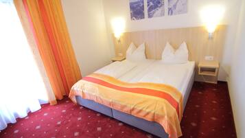 Een hotelkamer met een bed, twee nachtkastjes, een rood tapijt en twee wandlampen.