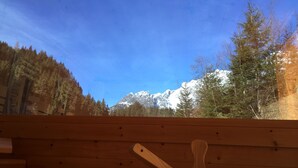 A wooden cabin with a view of a snowy mountain range and trees. - Hotel-Restaurant Bike&Snow Lederer (Muehlbach Am Hochkoenig)