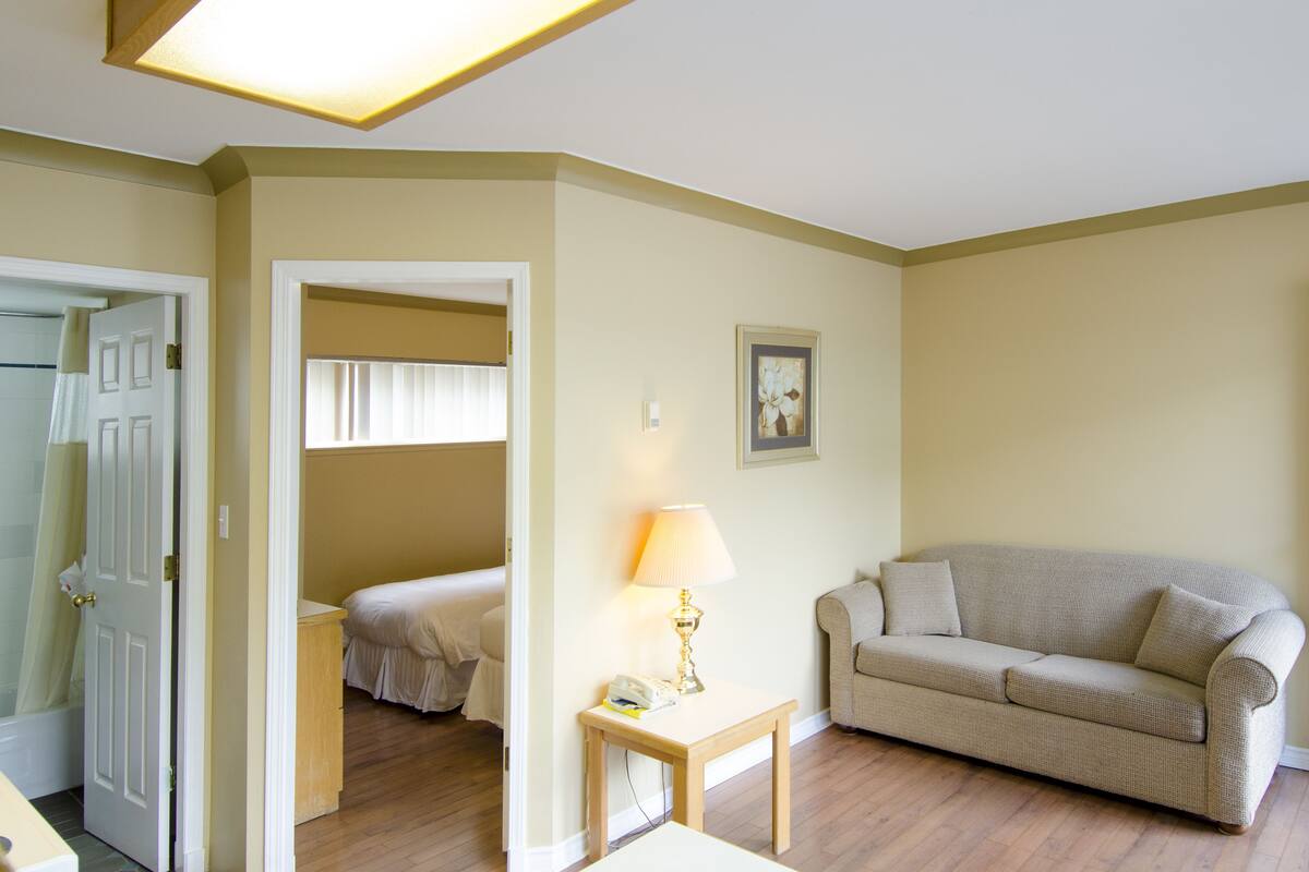 A hotel room with a bed, a sofa, a lamp, and a picture on the wall.