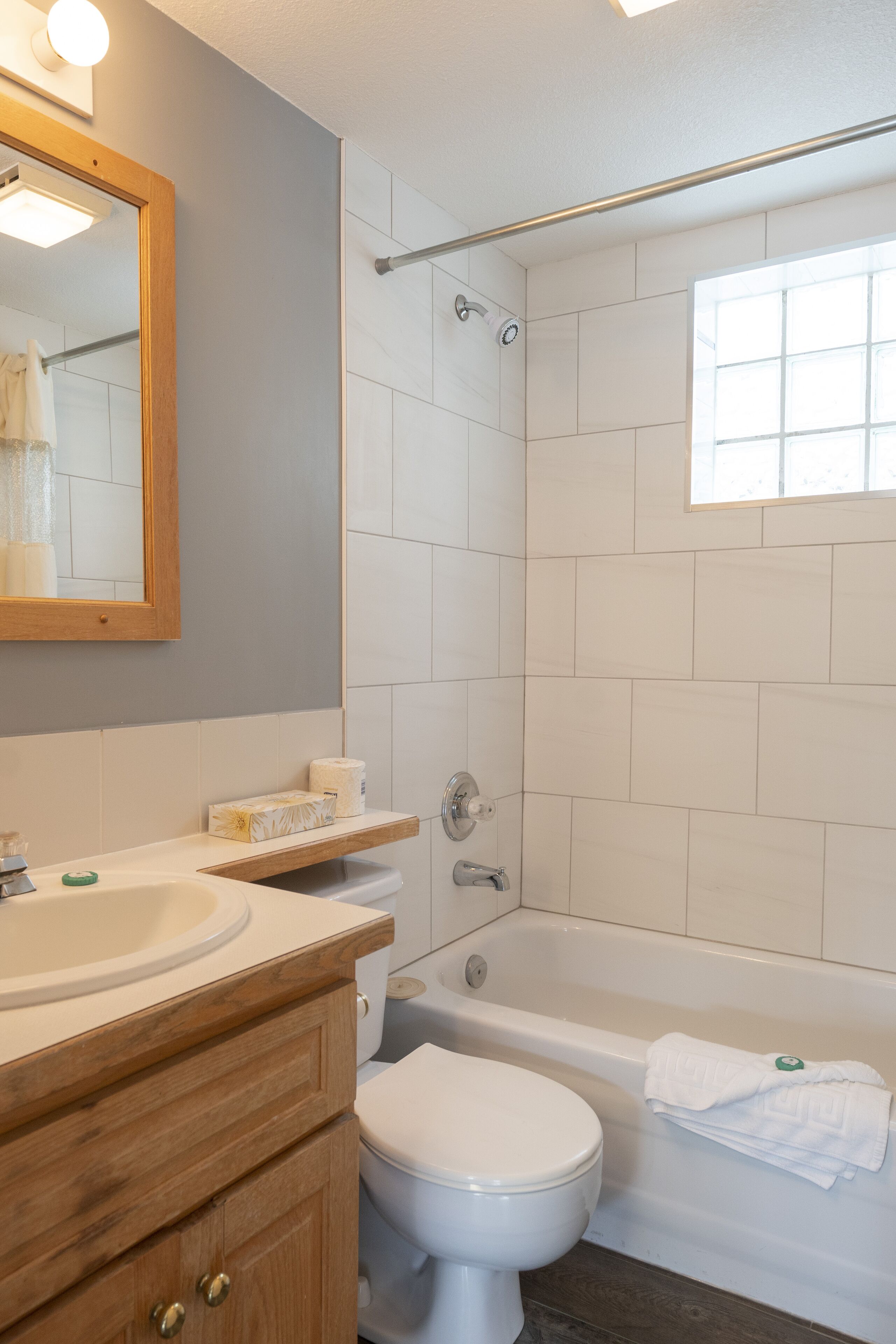 A bathroom with a white sink, wooden vanity, a toilet, a bathtub, and a shower with a glass door.