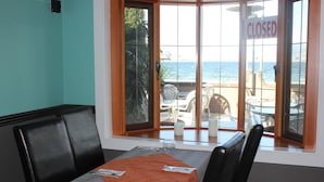 A restaurant with a table set for two, a view of the beach, and a 'CLOSED' sign on the window. - Tiki Shores Inn & Suites (Penticton)