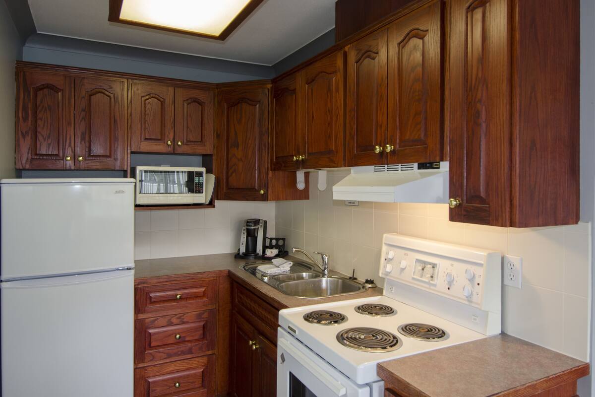 A kitchen with wooden cabinets, a microwave, a stove, and a refrigerator.
