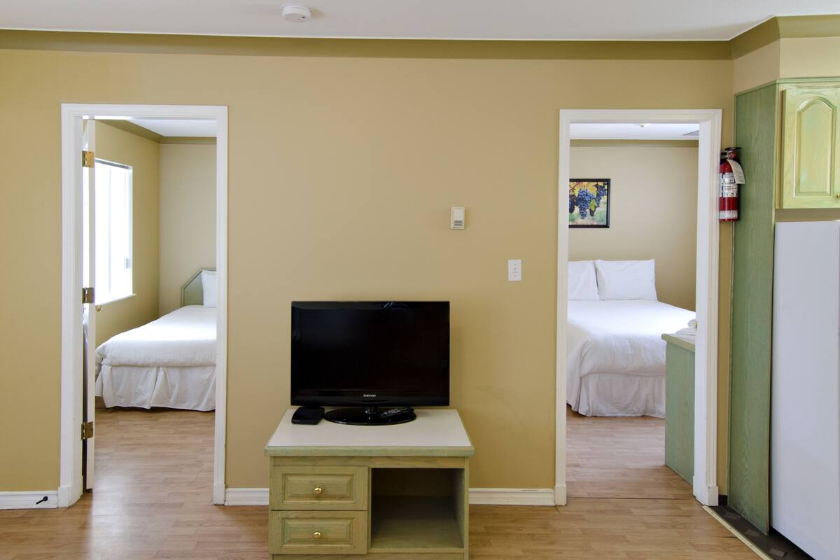 A room with two beds, a television, and a small desk.