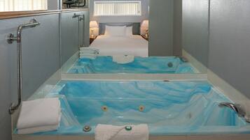 A bathroom with a large bathtub, a shower, and a toilet. There are towels and toiletries on the floor.
