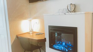 Una sala de estar moderna con chimenea, televisor montado y una mesa de comedor de madera con una silla.