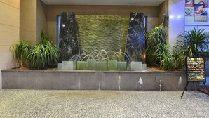 A reception area with a stone wall, marble pillars, a water feature, and potted plants. - Sunon Hotel (Shenzhen)