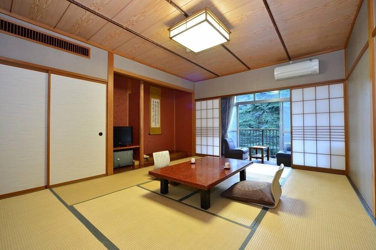 A traditional Japanese room with tatami flooring, a low table, a sofa, and sliding doors.