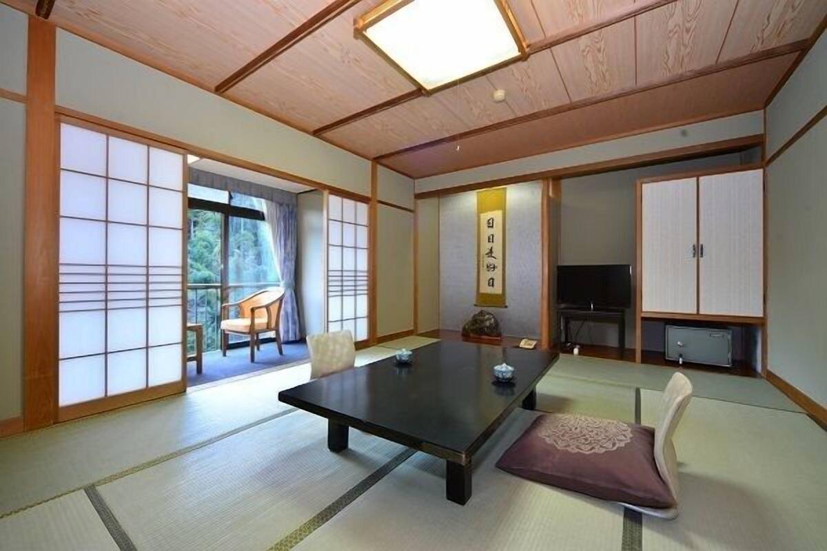 A traditional Japanese room with tatami flooring, a low table, and sliding doors.