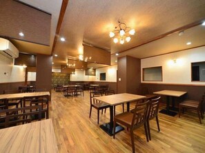 A restaurant with wooden tables and chairs, recessed ceiling lights, and a central dining area. - Ootaki Hotel (Yugawara)