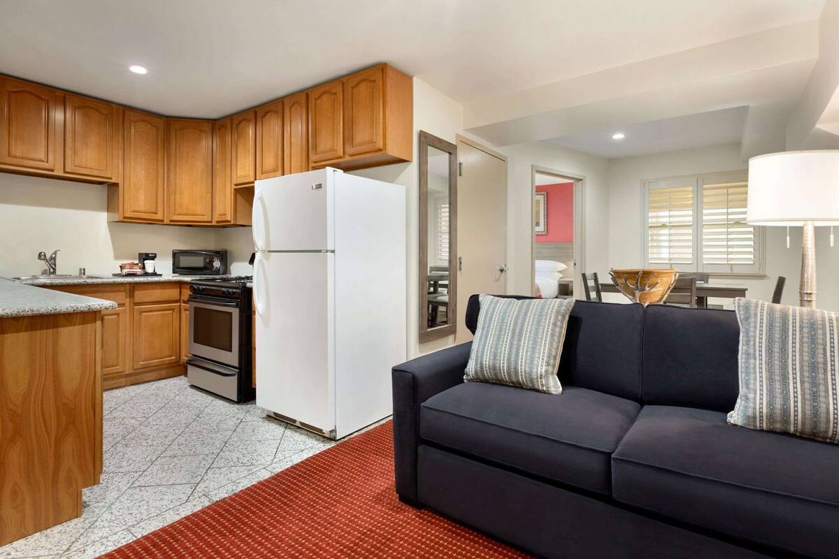 A compact kitchen with wooden cabinets, a white refrigerator, a stove, and a microwave.