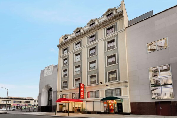 A multi-story building with a prominent 'RAMADA' sign, large windows, and a red awning. - Ramada by Wyndham Oakland Downtown City Center (Oakland)