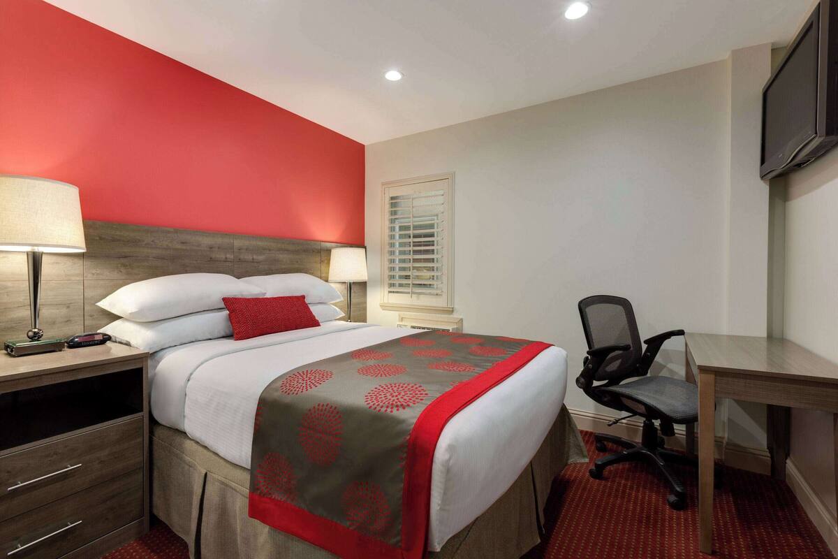 A hotel room with a bed, bedside tables, a desk, and a chair.
