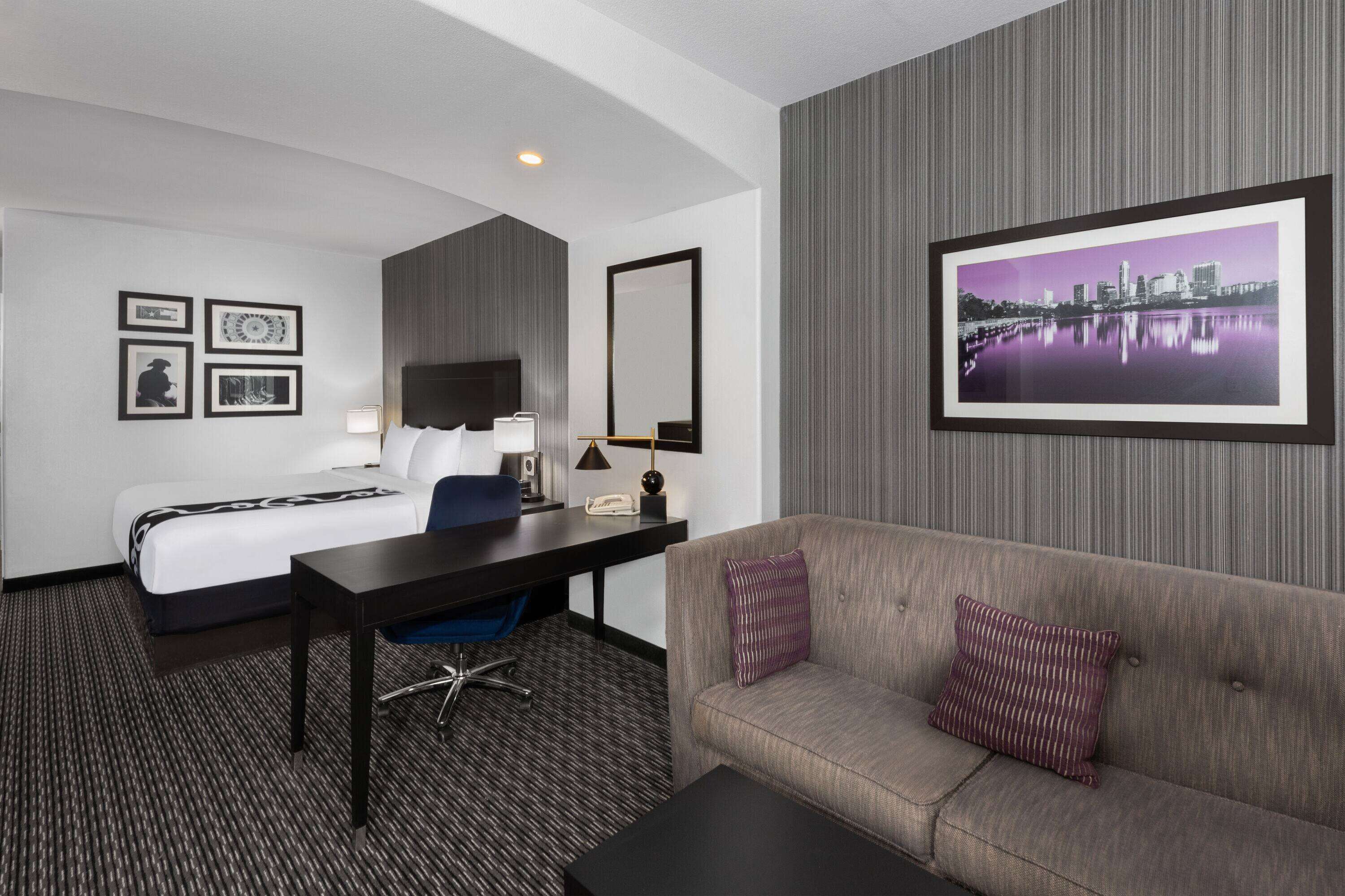 Una habitación de hotel con cama, escritorio, silla y sofá.