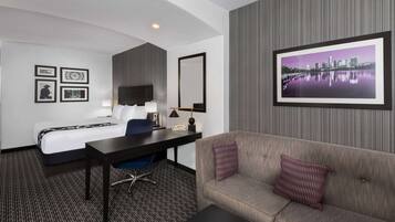 Una habitación de hotel con cama, escritorio, silla y sofá.