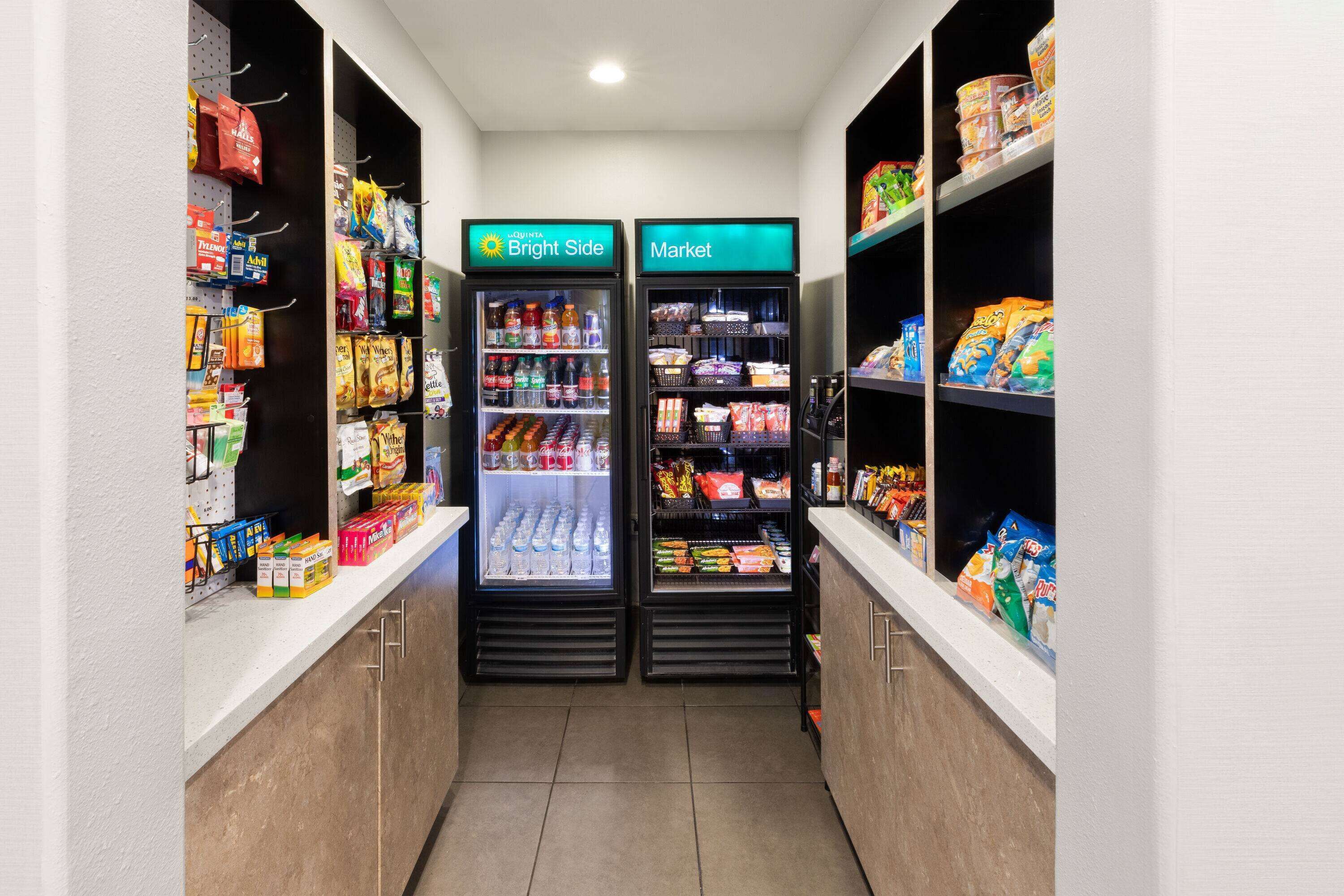 A narrow hallway with two refrigerated beverage dispensers labeled "Bright Side" and "Market," stocked with various drinks and snacks.