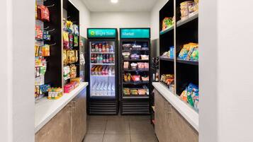 A narrow hallway with two refrigerated beverage dispensers labeled "Bright Side" and "Market," stocked with various drinks and snacks.