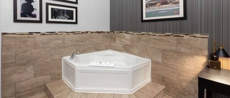 A modern bathroom with a freestanding bathtub, tiled walls, and framed pictures on the wall.