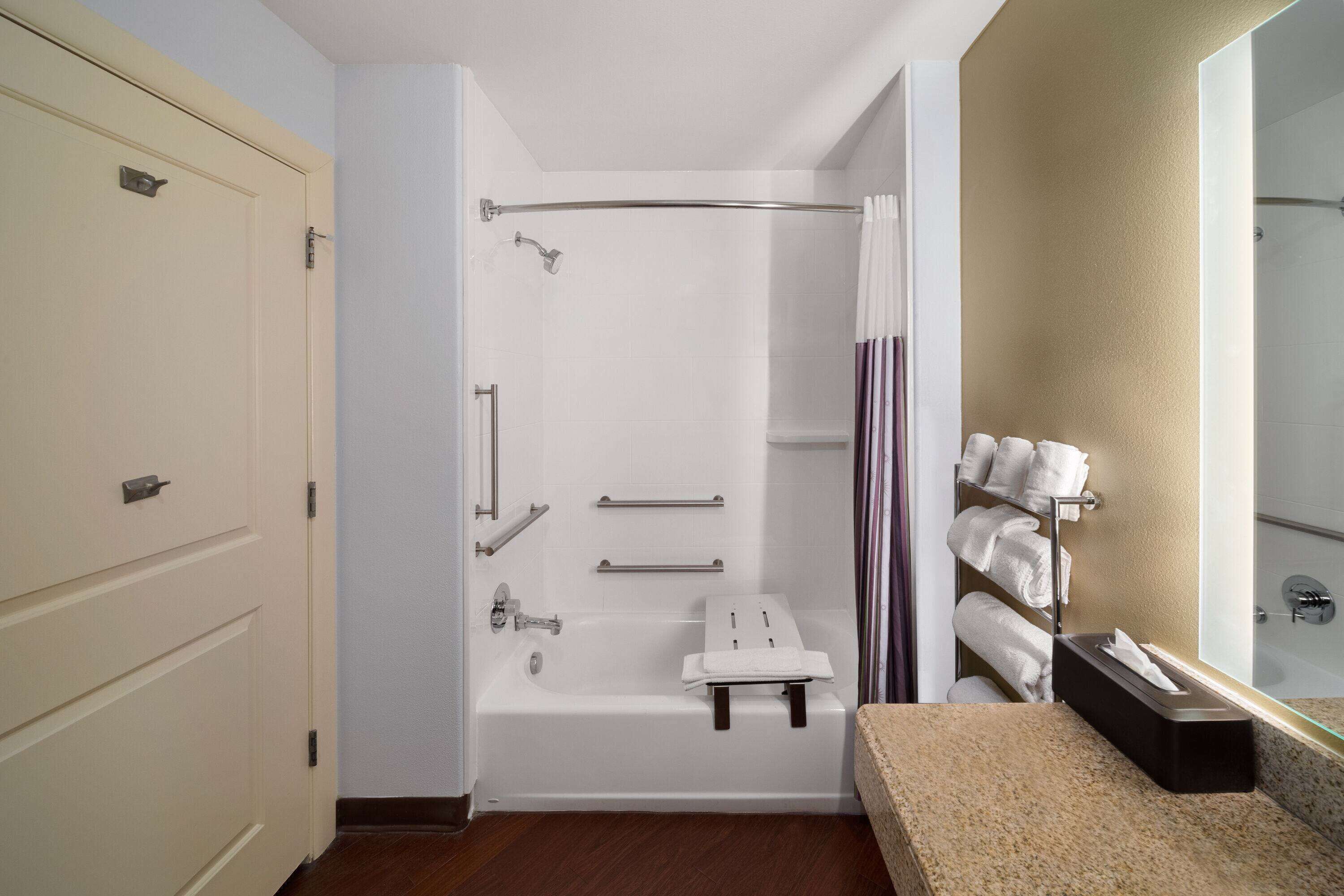 A modern bathroom with a bathtub, shower, and a vanity with a mirror.