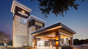 A hotel entrance with a modern design, a covered parking area, and a clear sky.