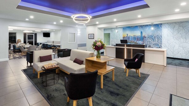 A modern hotel lobby with a reception desk, seating area, and a cityscape mural.