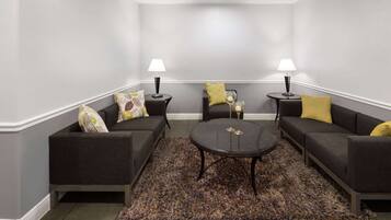 A modern living room with two dark sofas, a round coffee table, and two side tables with lamps.