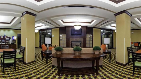 A hotel lobby with a round table, sofas, and a fireplace.