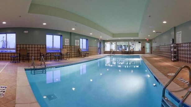 An indoor swimming pool with clear water, surrounded by seating areas and windows. - Holiday Inn Express Hotel & Suites Richwood-Cincinnati South by IHG (Walton)