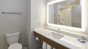 A bathroom with a toilet, a sink, a mirror, and a shower. - Holiday Inn Express Hotel & Suites Richwood-Cincinnati South by IHG (Walton)