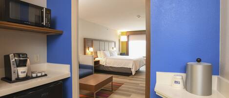 Ein Hotelzimmer mit Küchenzeile, einem Bett, einem Nachttisch und einem Badezimmer.