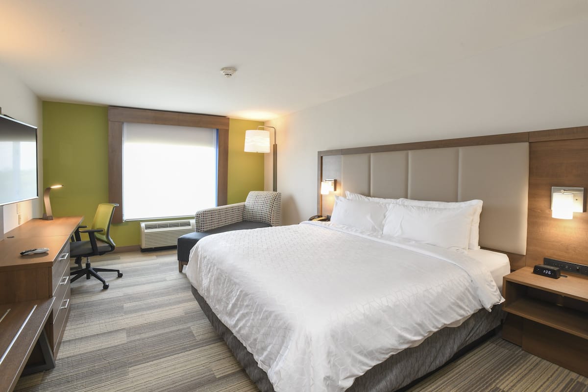 Une chambre d’hôtel avec un grand lit, un bureau, une chaise et une fenêtre.