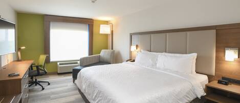 Una habitación de hotel con una cama grande, un escritorio, una silla y una ventana.