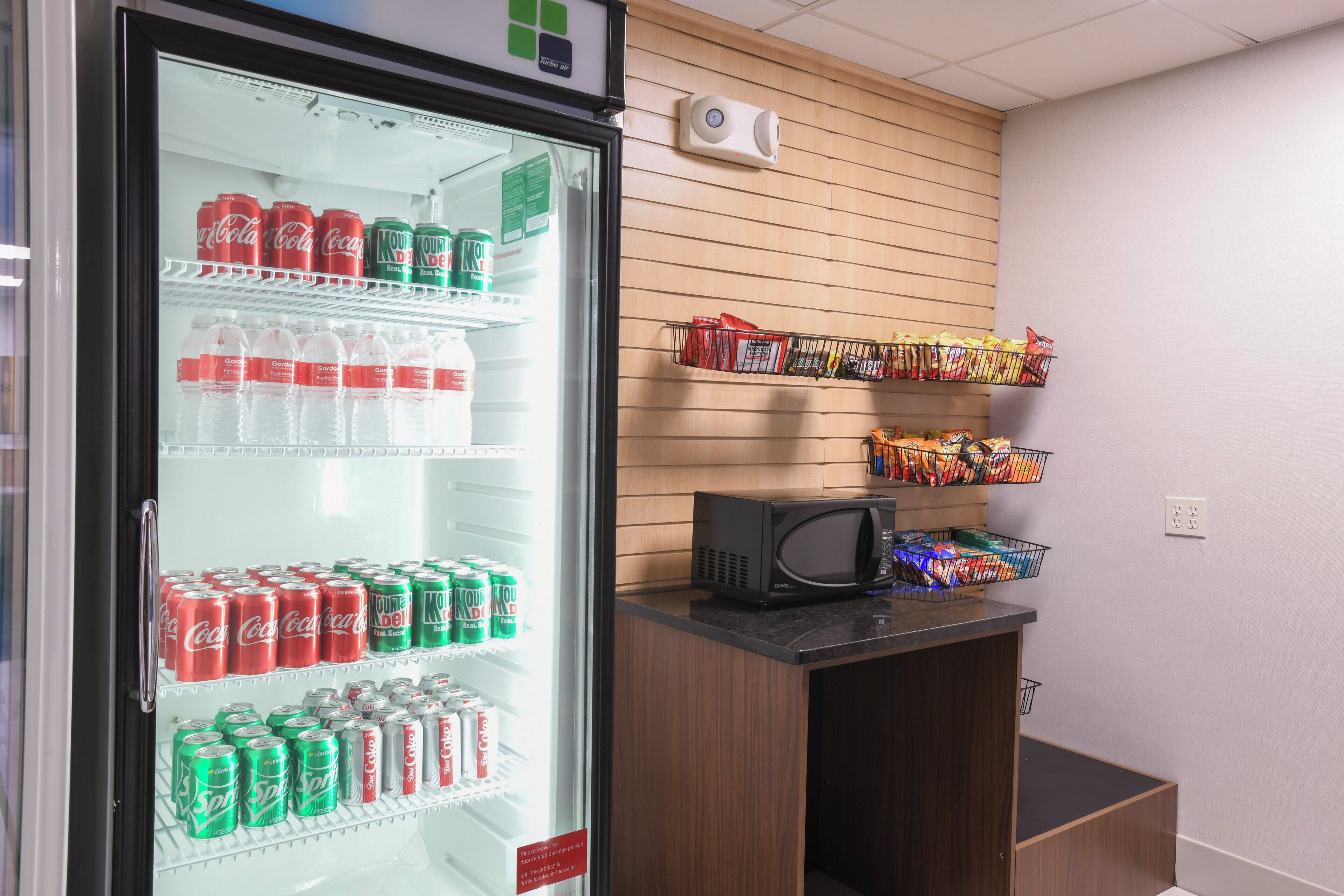 A refrigerator stocked with various beverages and a microwave on a counter.
