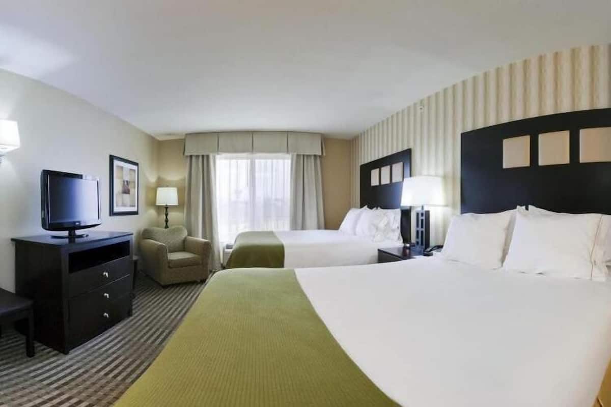 Une chambre d’hôtel avec deux lits, un bureau avec une télévision, une chaise et une lampe.