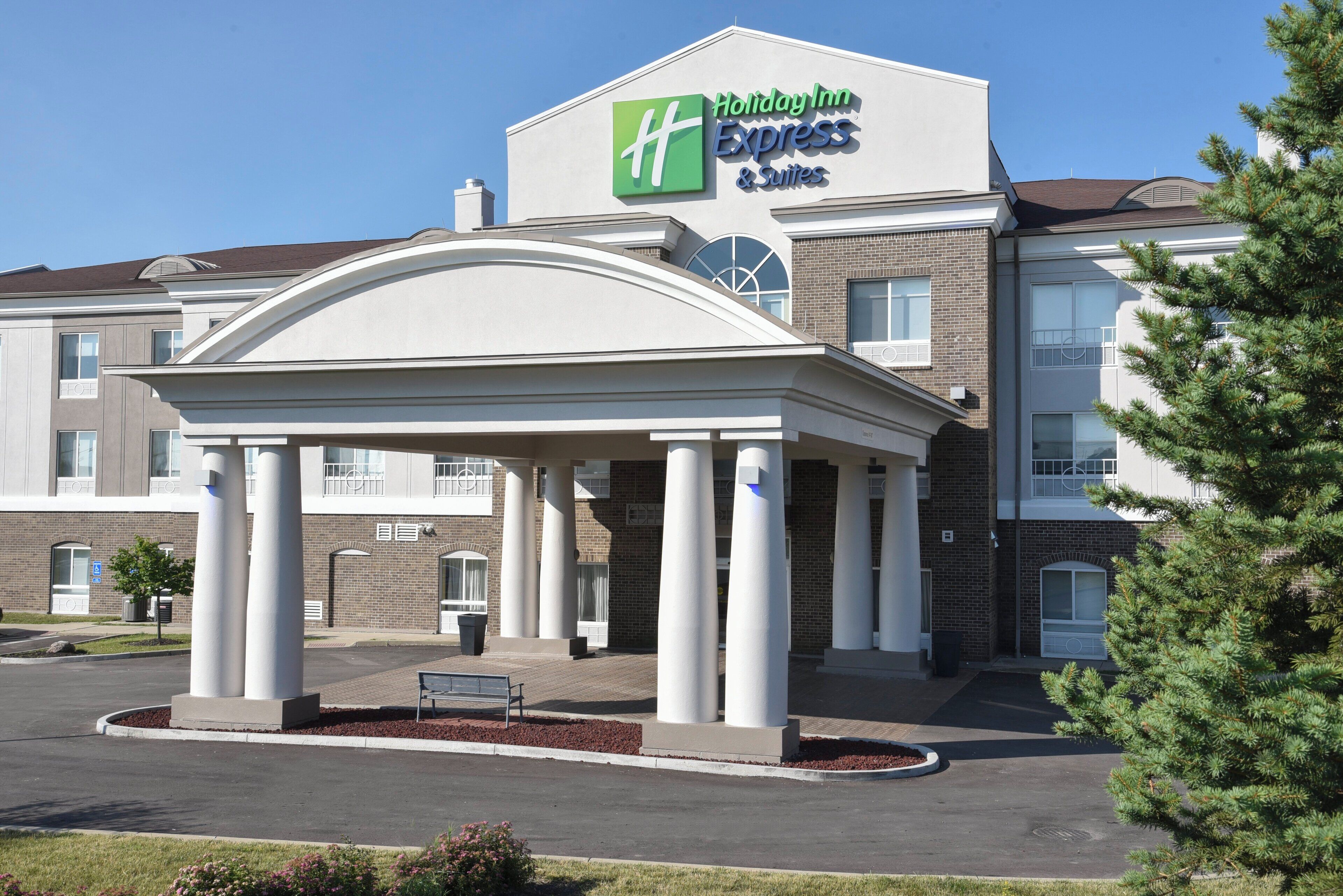 Holiday Inn Express & Suites -hotellin rakennus, jossa on katettu sisäänkäynti ja tiiliverhoiltu julkisivu.