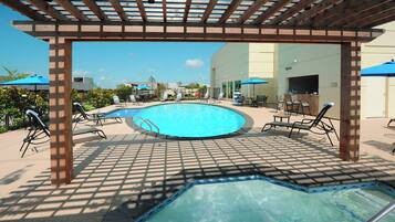 Alberca al aire libre, sombrillas en la alberca y camastros