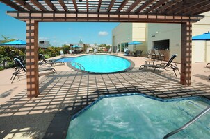 Una piscina al aire libre, sombrillas, sillones reclinables de piscina