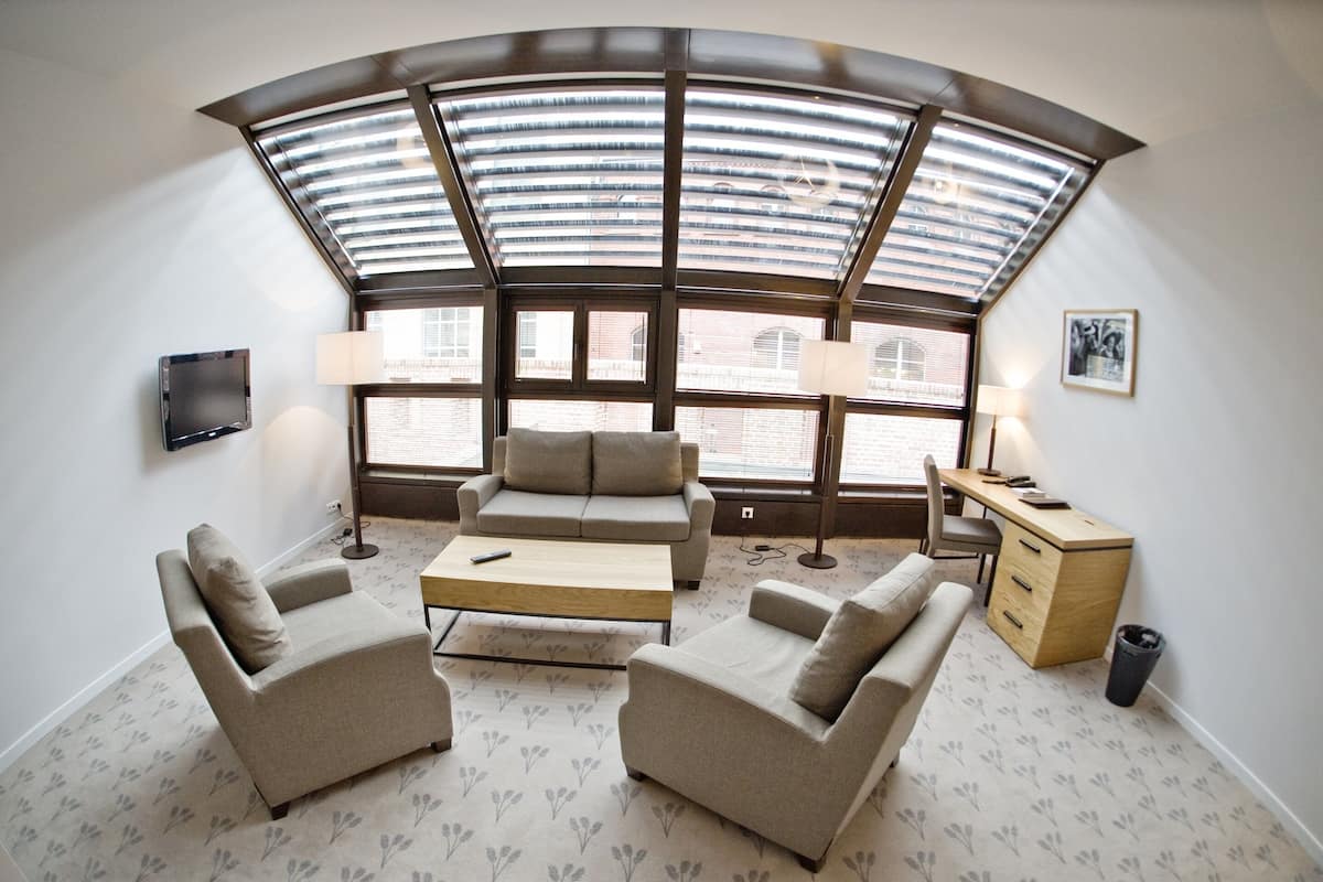 A modern room with a curved ceiling skylight, two sofas, a coffee table, a desk with a lamp, and a TV mounted on the wall.