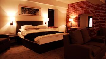 Habitación de hotel con una cama grande, dos lámparas de noche, una pared de ladrillo y un cuadro enmarcado.