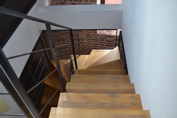 A staircase with wooden steps and metal railings, leading to a higher floor.
