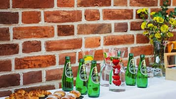 A table with pastries and green bottles labeled 'King Pie' against a brick wall.