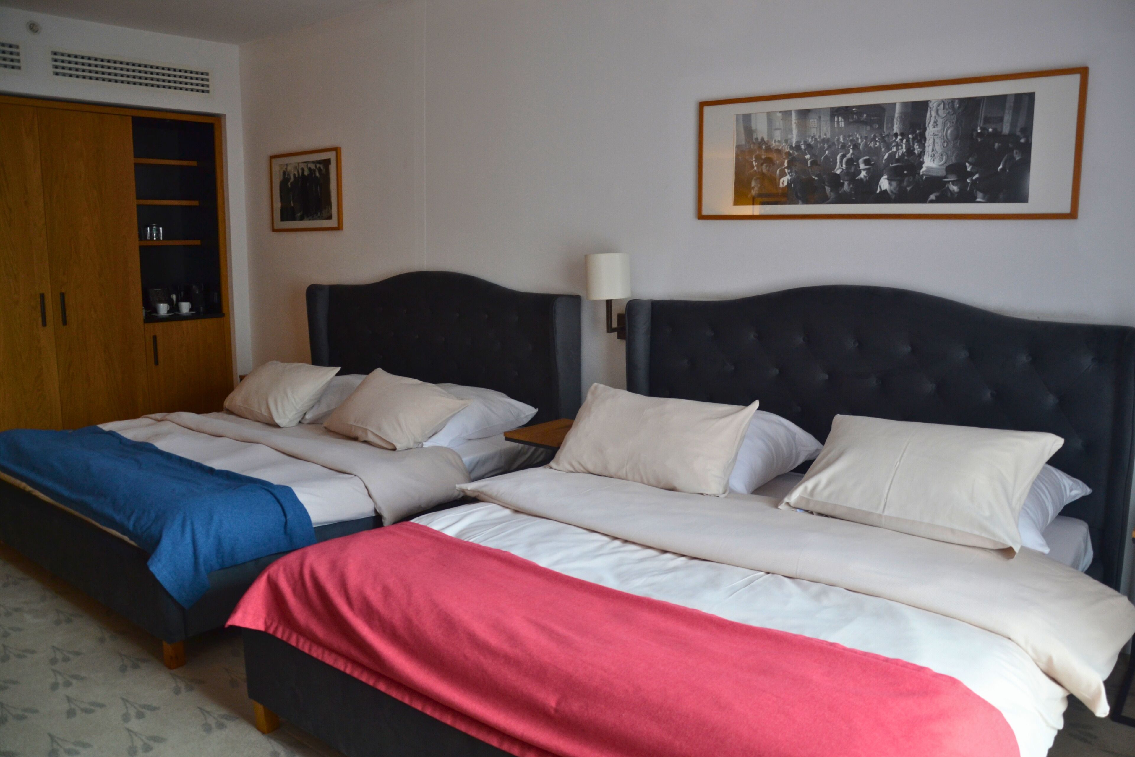 A double bed with a headboard, a wardrobe, and a framed picture on the wall.