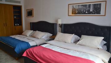 A double bed with a headboard, a wardrobe, and a framed picture on the wall.