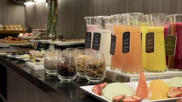 Un bufé con diversas opciones de comida y bebida, como frutas, yogur y jugos.