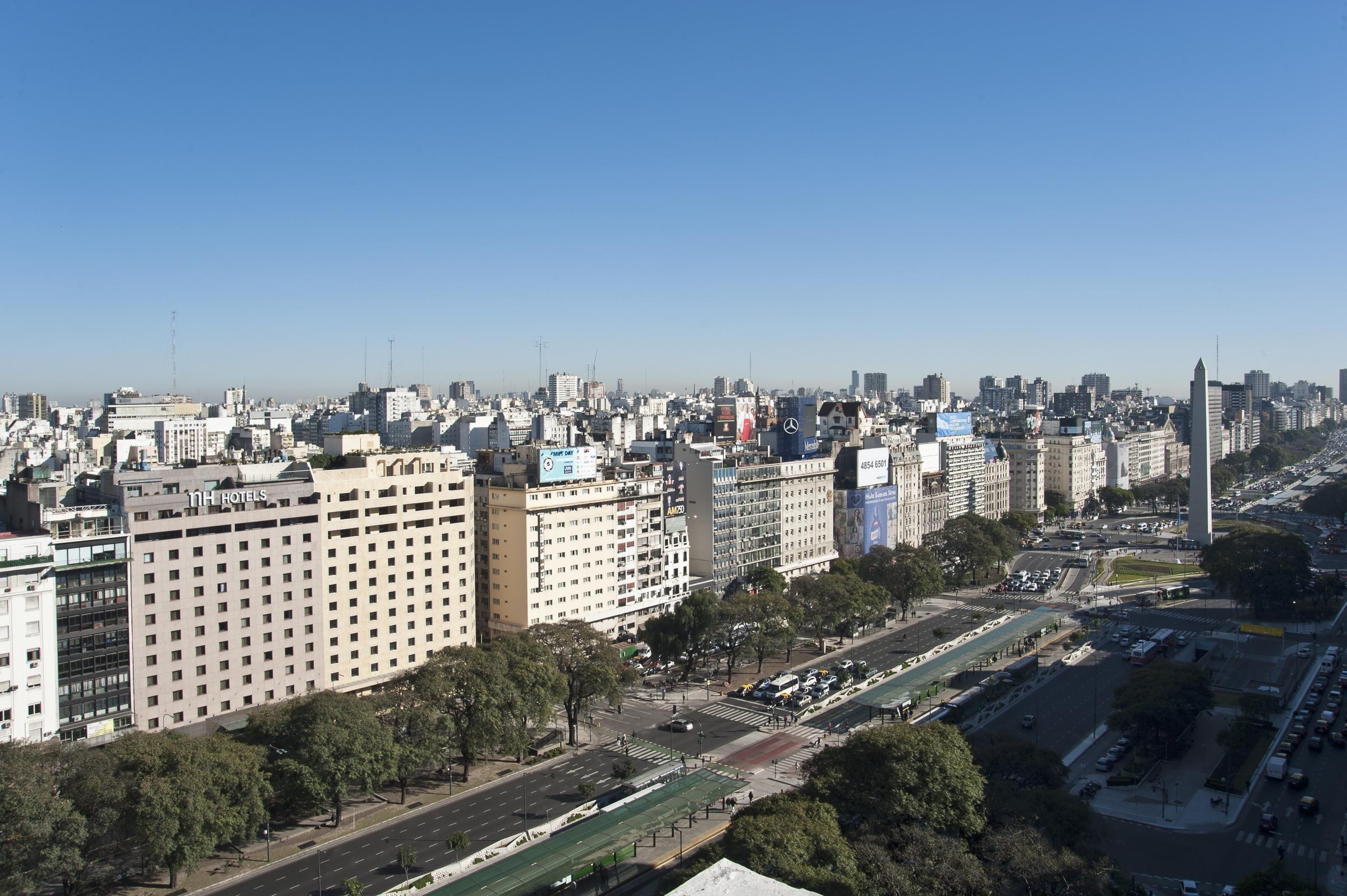 A cityscape with a prominent 11th Hotel building, surrounded by other high-rise buildings and a busy street with a green bike lane.