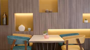 Un comedor moderno con una pared de madera, una mesa y dos sillas con tapicería verde aguamarina y amarilla.